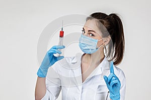 Woman doctor in mask and rubber gloves holding syringe