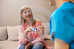 Woman doctor measures the patient& x27;s pulse and oxygen saturation to senior woman.