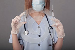 Woman doctor in medical mask and gloves. close-up. holds an ampoule with a vaccine and a syringe in his hands. covid