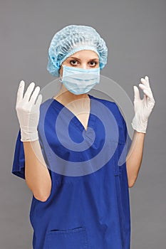 Woman doctor in the medical uniform, with sterile gloves on the hands and a mask on the face