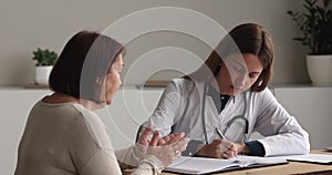 Woman doctor noting complaints and health concerns of older patient