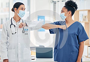 Woman doctor and nurse, in a hospital elbow greeting, in surgical mask during the covid pandemic. Teamwork, healthcare