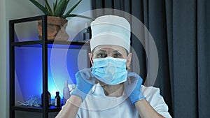 Woman doctor or nurse in protective medical wear puts on medical face mask in research laboratory office. Portrait of woman is put