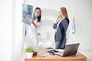 Woman doctor and patient in hospital looking at x-ray film healthcare, roentgen, people medicine concept.