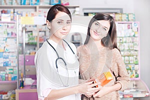 Woman doctor in pharmacy with box of drugs in hand with a client