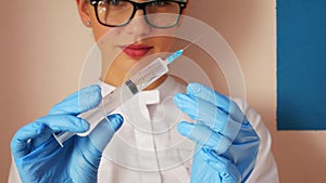Woman doctor preparing syringe for injection. Female doctor or nurse holding syringe with liquid close up. Medicine and