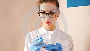 Woman doctor preparing syringe for injection. Female doctor or nurse holding syringe with liquid close up. Medicine and