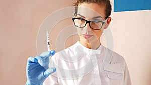 Woman doctor preparing syringe for injection. Female doctor or nurse holding syringe with liquid close up. Medicine and