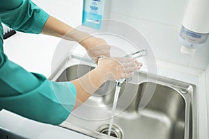 A woman doctor in protective mask washes hands thoroughly in hospital