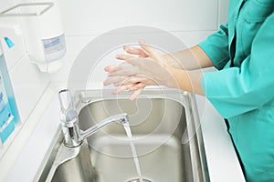 A woman doctor in protective mask washes hands thoroughly in hospital