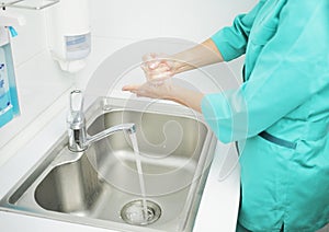 A woman doctor in protective mask washes hands thoroughly in hospital