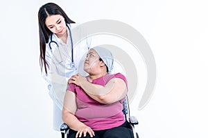 Woman doctor put hand is placed on the shoulders of a female patient Which sat on wheelchair to encourage