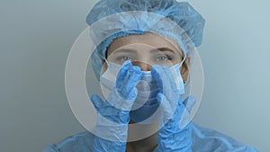 Woman doctor puts on medical face mask preparing to surgical treatment. Beautician in medical face mask preparing to work. Female