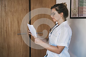 Woman doctor reading papers in office