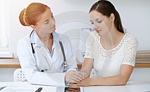 Woman-doctor reassuring her female patient while sitting at the desk. Medicine concept