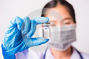 Woman doctor or scientist wearing face mask protective in lab holding medicine liquid vaccines