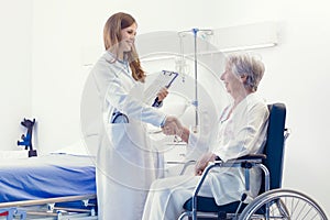 Woman doctor shaking hands with an elderly patient