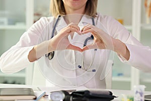 Woman doctor showing heart shape sign with hands