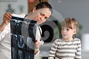 Woman doctor shows child patient an xray in clinic
