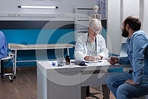 Woman doctor signing checkup files to give treatment to man after examination