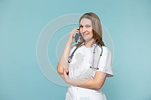 A woman doctor with a smartphone conducts an online consultation, supports the patient by phone, on a blue background