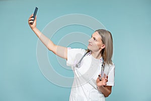 A woman doctor with a smartphone takes a selfie, on a blue background. Copy paste. healthcare concept.