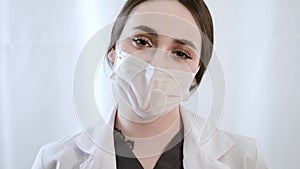 Woman doctor speaking with mask while looking at camera.