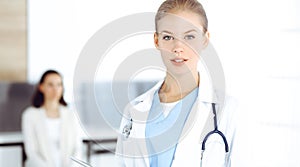 Woman - doctor standing in clinic. Physician at work, studio portrait. Medicine and health care concept