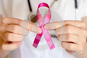 Woman doctor keeps a pink ribbon close up. Breast cancer examination concept