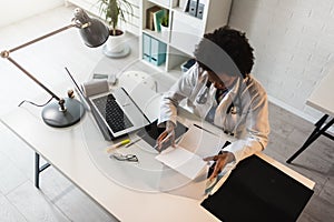 Woman doctor with stethoscope looking at medical papers at her office working hard