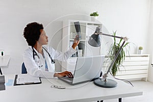 Woman doctor with stethoscope looking at medical papers at her office working hard