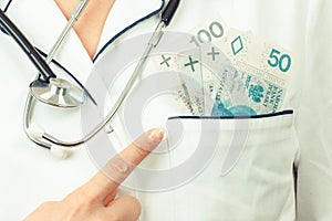 Woman doctor with stethoscope showing polish currency money in apron pocket