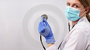 Woman doctor with stethoscope on white wall