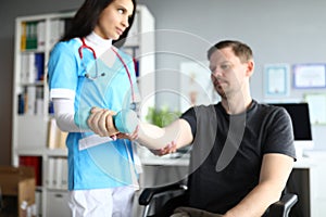 Woman in doctor suit and red stethoscope examine visitor hand for fracture.