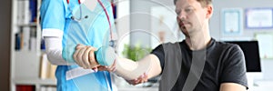 Woman in doctor suit and red stethoscope examine visitor hand for fracture.