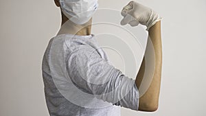 Woman doctor with a surgical mask and white rubber gloves in position of  Rosie the Riveter