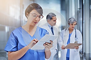 Woman, doctor and tablet in hospital with scrubs for medical, check on digital file for schedule. Female surgeon