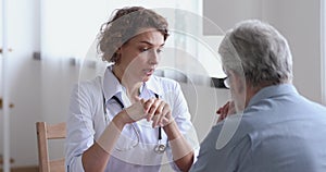 Woman doctor talking examining senior patient at visit in hospital