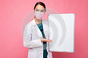 Woman doctor wearing a white medical coat and a mask holding blank board with copy space for text isolated on background