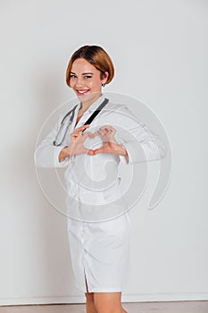 woman doctor in white coat with phonendoscope shows heart