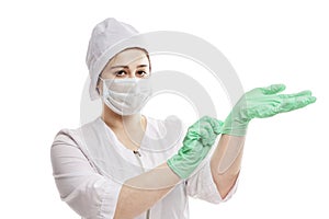 Woman Doctor in a white halya and a cap puts on medical gloves. Precautions during the coronavirus pandemic. Isolated on a white