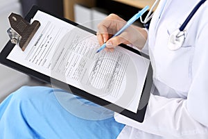 Woman doctor at work at hospital. Young female physician write prescription or filling up medical form while sitting in