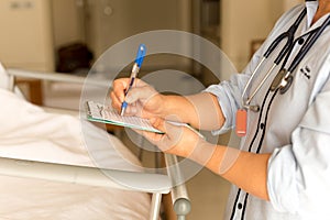 Woman doctor writing medical details of patient