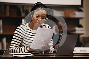 Woman, documents and headphones in library for research, studying and computer research or planning in university