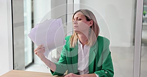 Woman with documents suffers from heat in office