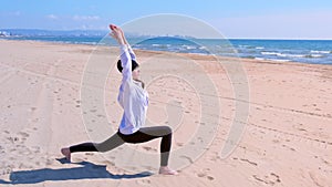 Woman does High Lunch Pose on sea sand beach yoga training sport exercise.