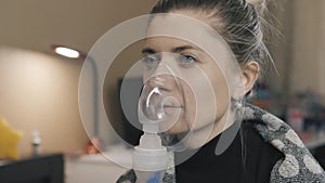 Woman does inhalation using an inhaled asthmatic portable nebulizer inhaler.