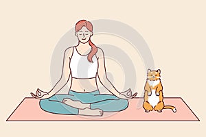 Woman does yoga with cat, meditating in lotus position from zen or asana practice