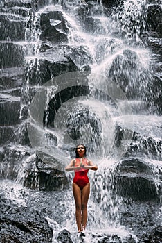 A woman does yoga at a waterfall. Healthy lifestyle. The concentration of the body. A woman does yoga in Bali. A woman meditates