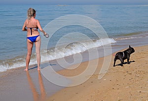 Woman with a dog on the beach by the sea